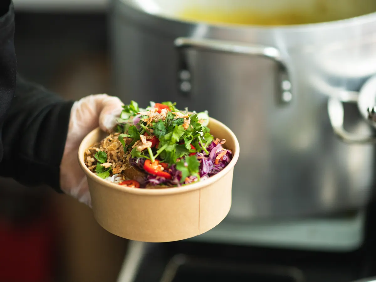 Fresh herb and red cabbage salad being added to a curry box at the Tippy's Thai stall