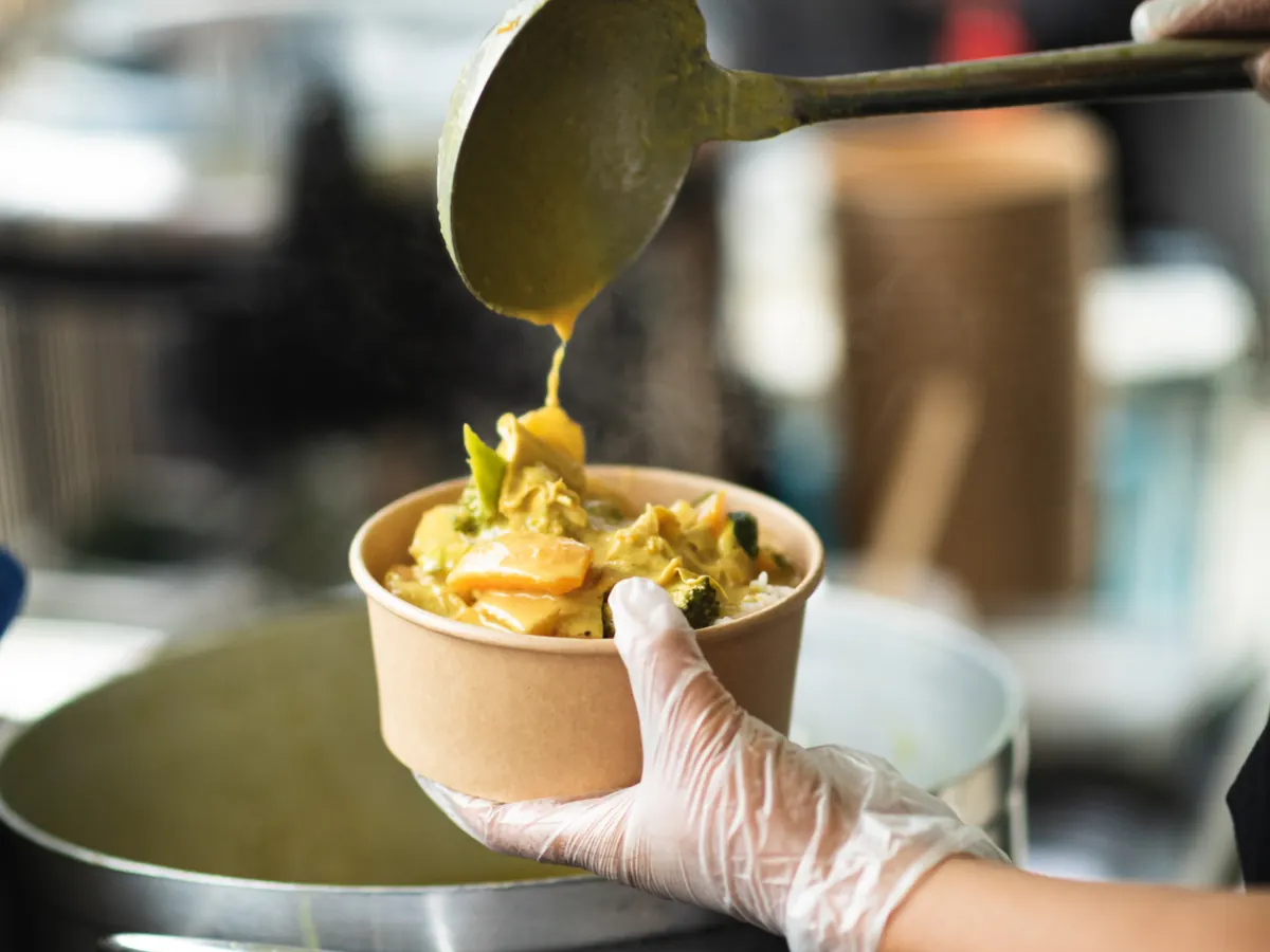Yellow curry being ladled fresh into a takeaway box at the Tippy's Thai stall