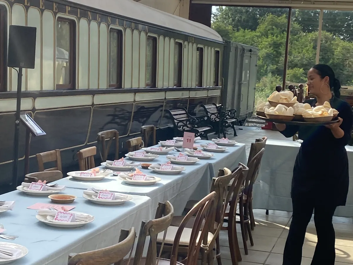 Tippy serving canapés at a wedding reception laid out beside a vintage railway carriage